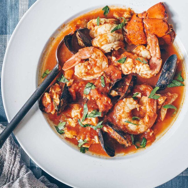 A large bowl of Fra Diavolo seafood stew, a tomato based stew with mounds of shrimp, mussels, calamari, and lobster tails.
