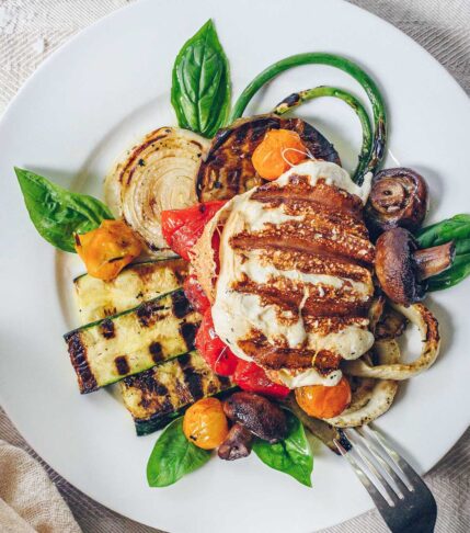 A plate of grilled summer vegetables topped with grilled smoked mozzarella.