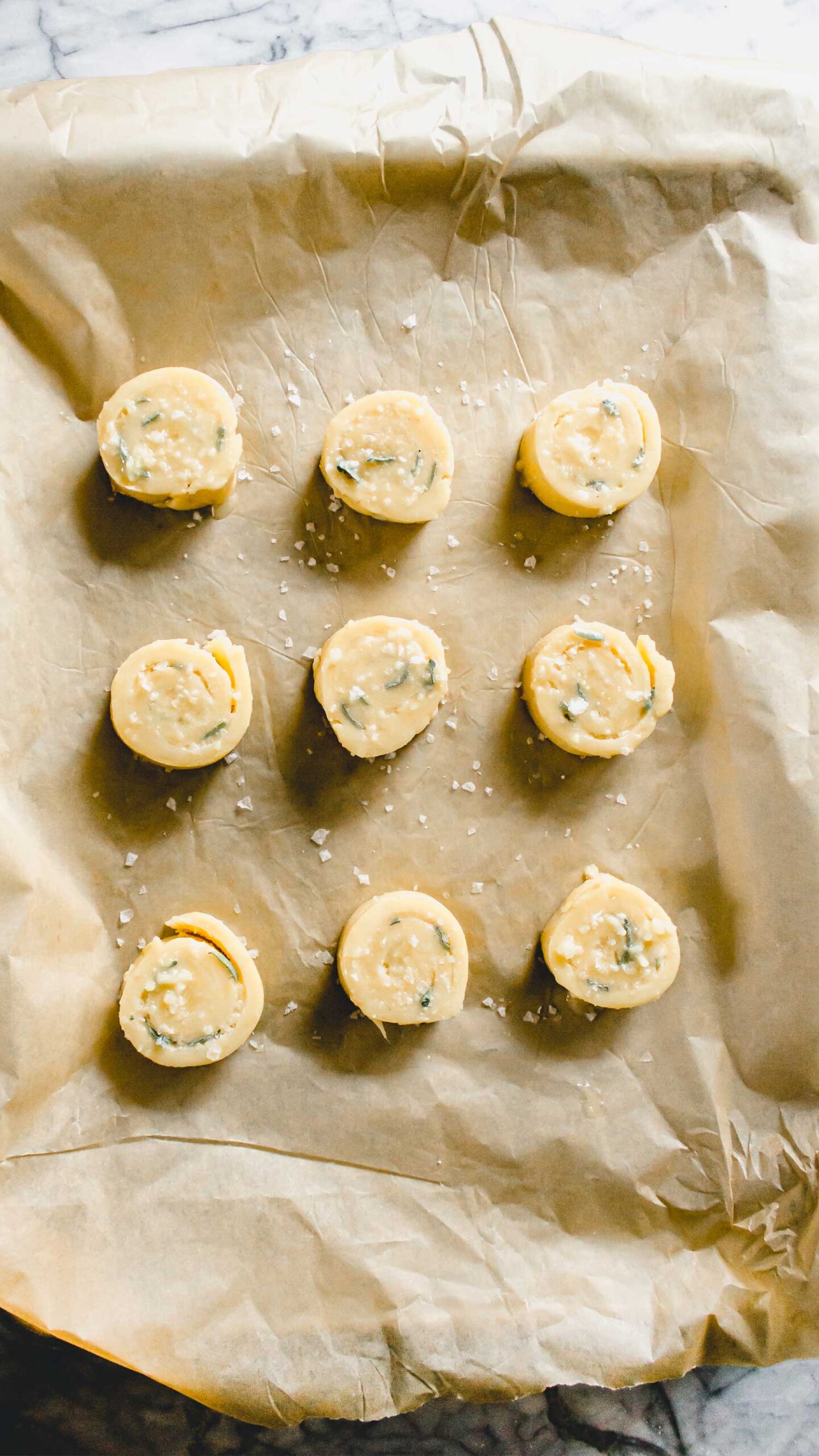Parmesan Sage Pinwheels on a baking sheet covered with parchment paper waiting to go in the oven.