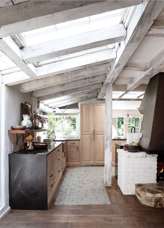 A modern rustic cottage kitchen with skylights and white plastered wooden beams.