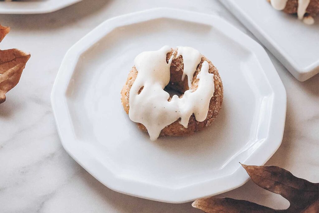 A closeup of a pumpkin spice donut drizzled with cream cheese glaze.