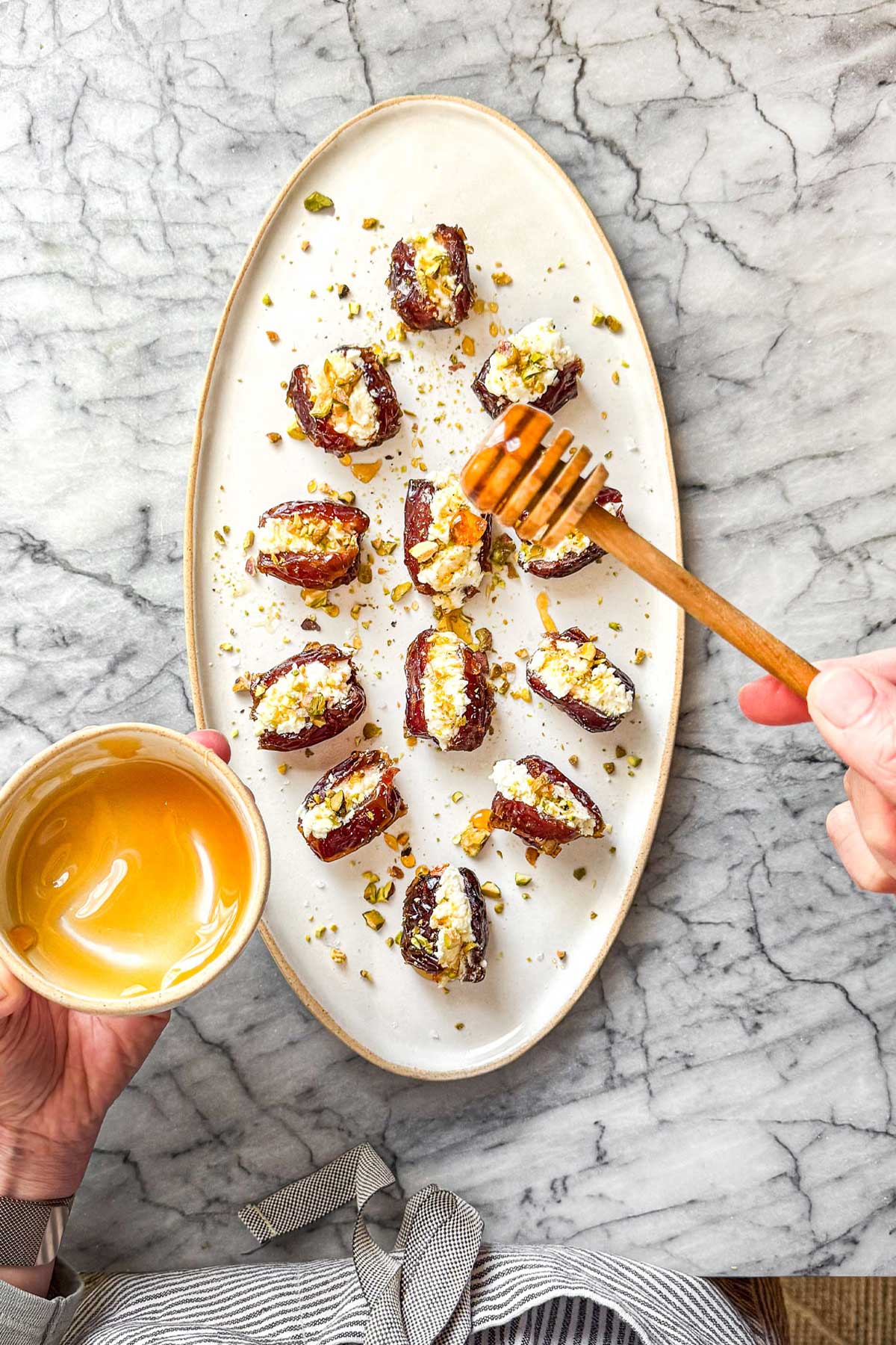Goat Cheese Stuffed Dates being drizzled with hot honey drizzle.
