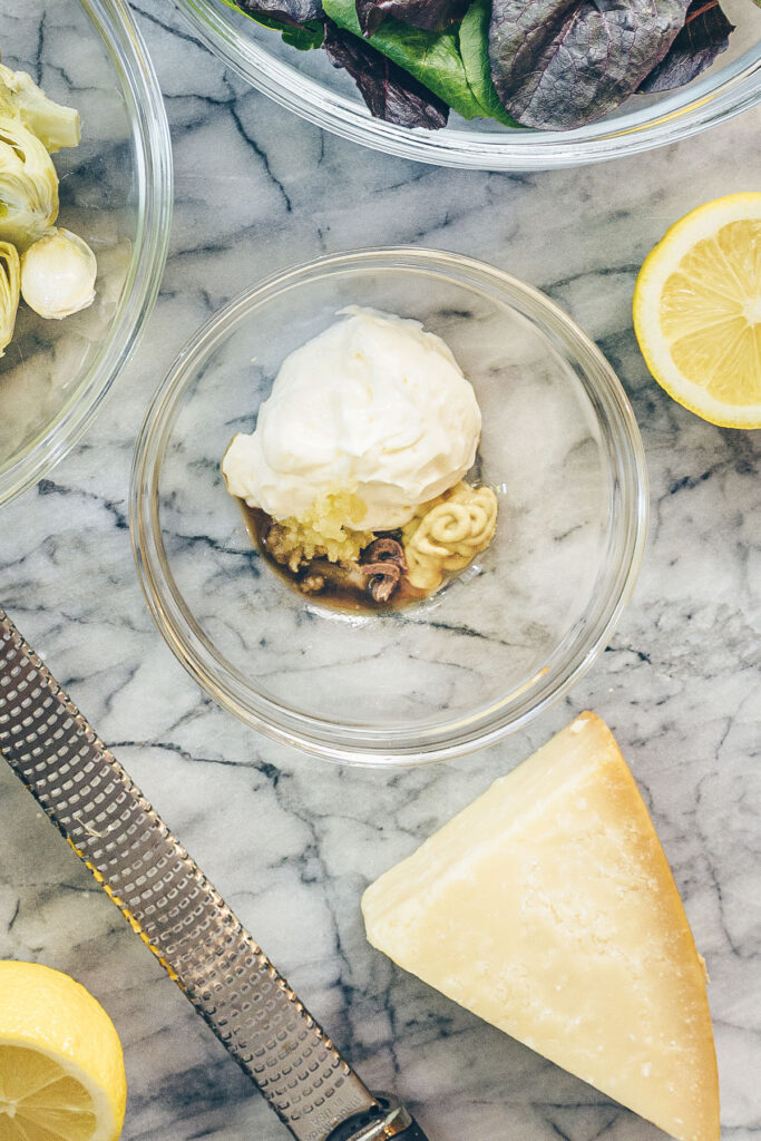 The ingredients for an easy Caesar Salad dressing (what I call my "Cheater's Caesar") in bowls on a marble countertop.
