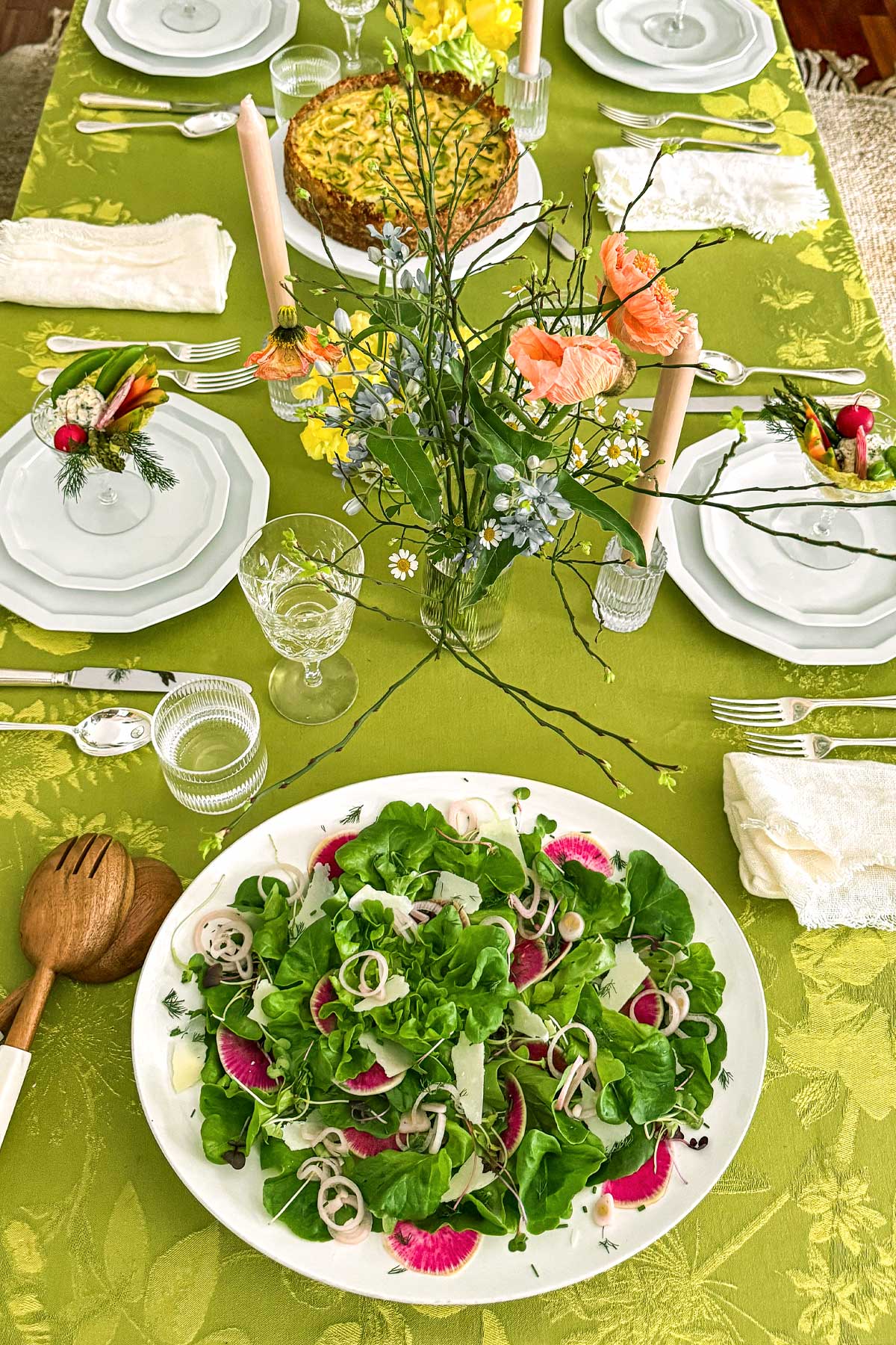 Early spring greens salad with butter lettuce, watermelon radishes, shaved parmesan, and pickled shallots being served on the table at a spring brunch.