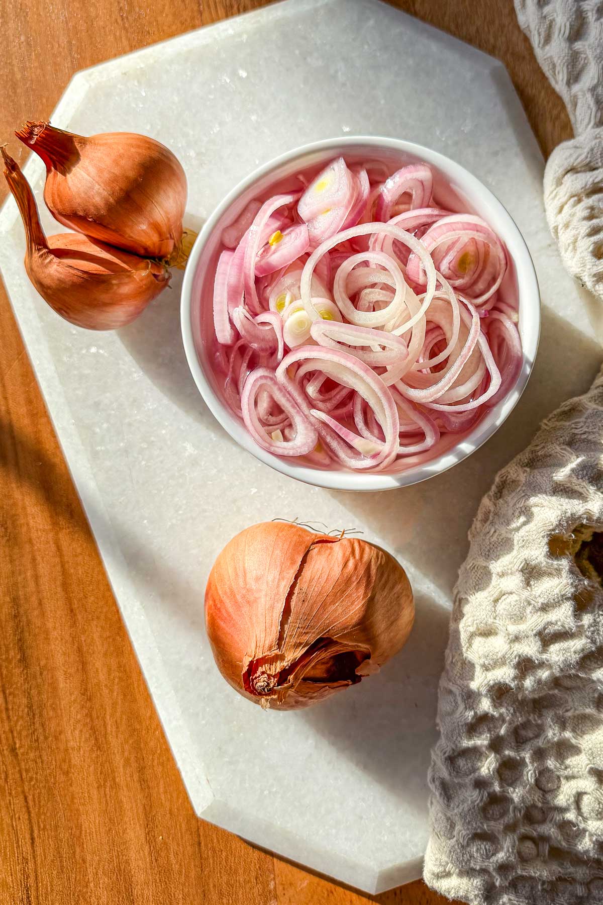 Quick pickled shallots in a ramekin sitting on a marble board.