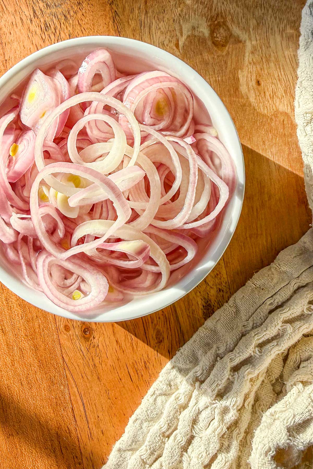 Quick pickled shallots in a ramekin sitting on a marble board.