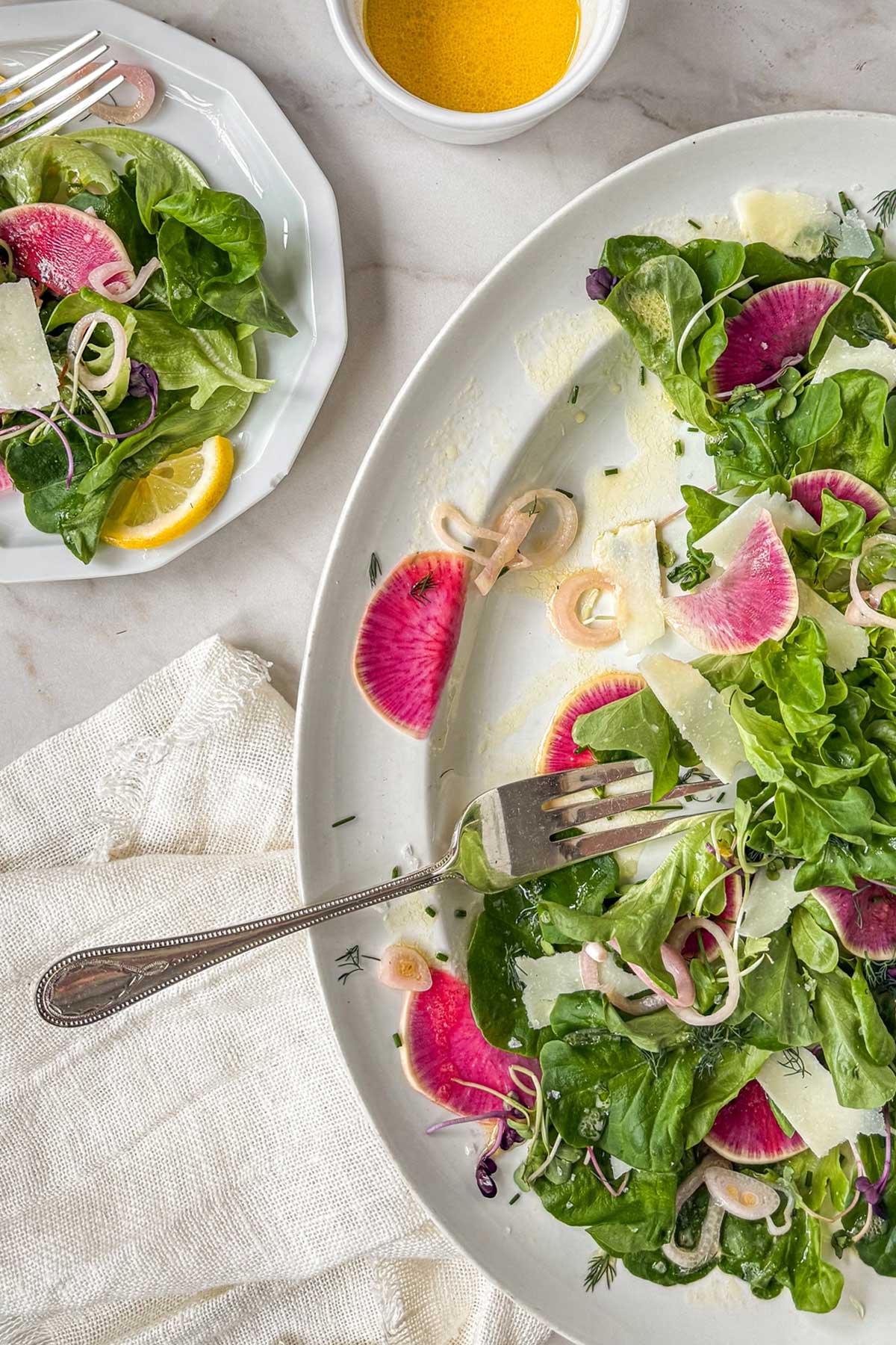 Quick pickled shallots scattered over an early spring greens salad wth watermelon radish.