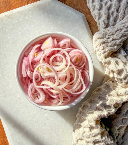 Quick pickled shallots in a ramekin sitting on a marble board.