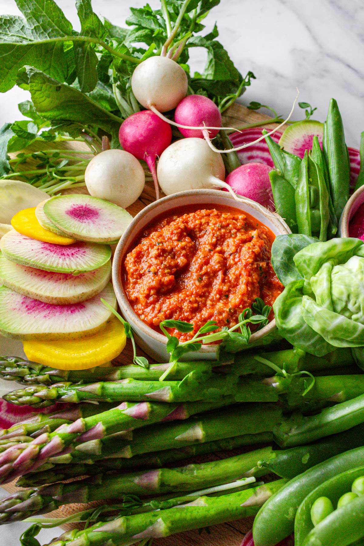 Spring crudite platter with asparagus, watermelon radish, snap peas, and roasted vegetable dip