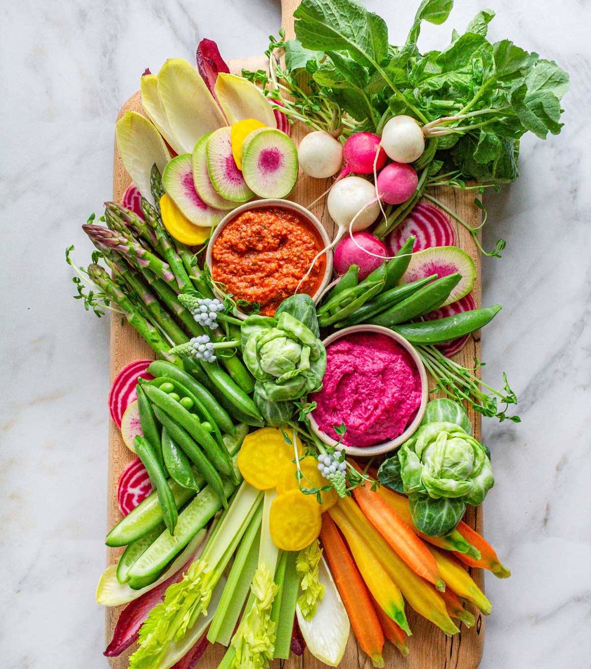 Spring vegetable crudite platter with asparagus, radishes, snap peas, and dips