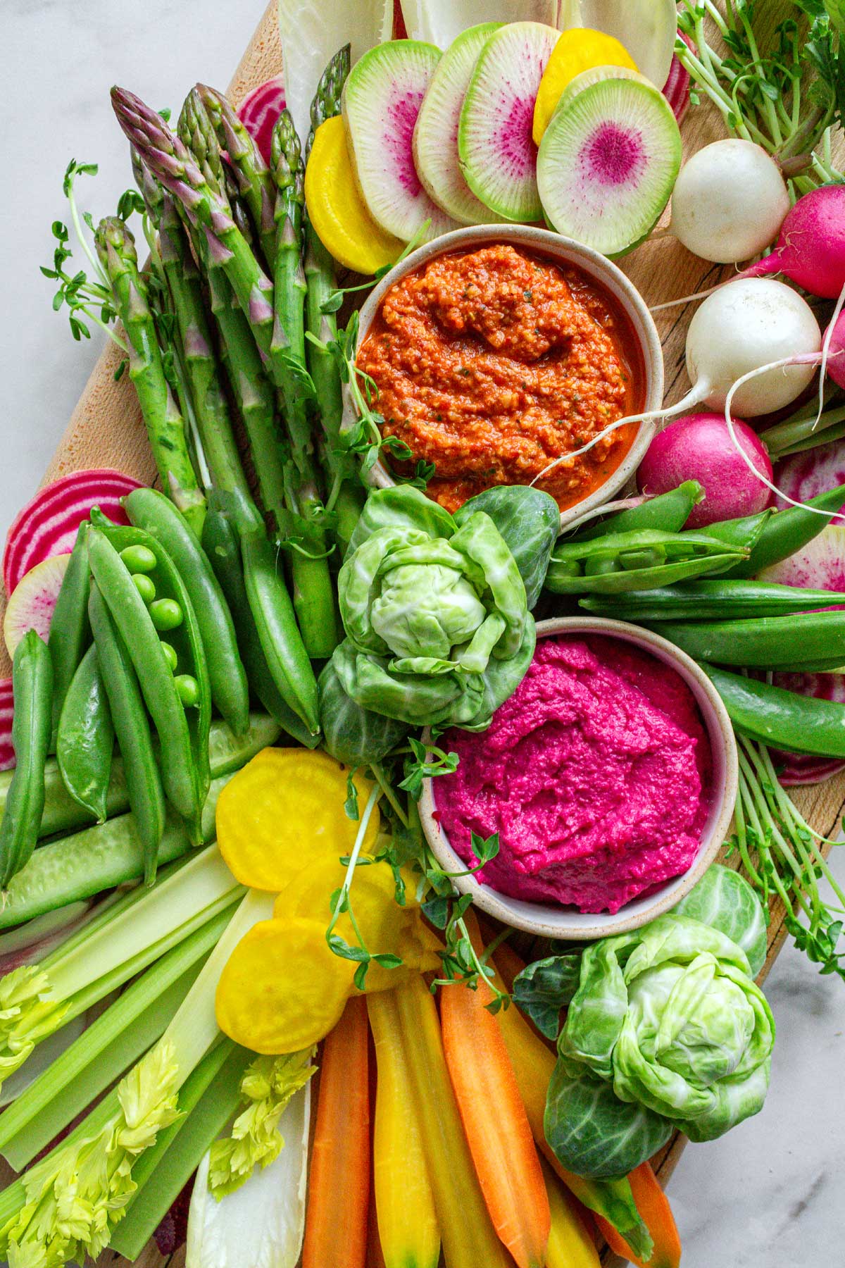 Spring crudite platter with asparagus, watermelon radish, snap peas, and roasted vegetable dip