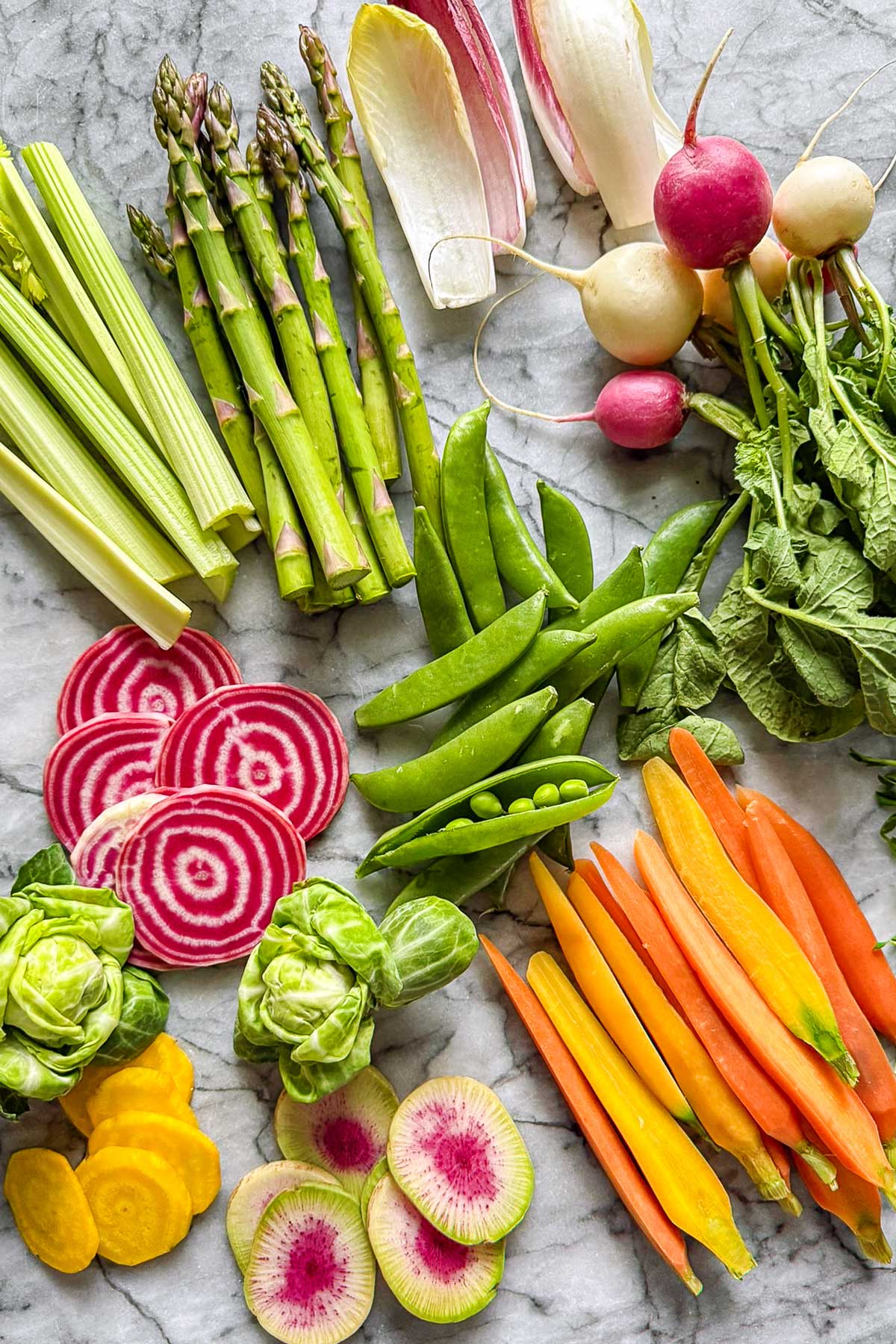 Fresh spring vegetables for a crudite platter including asparagus, radishes, snap peas, carrots, celery, and watermelon radish