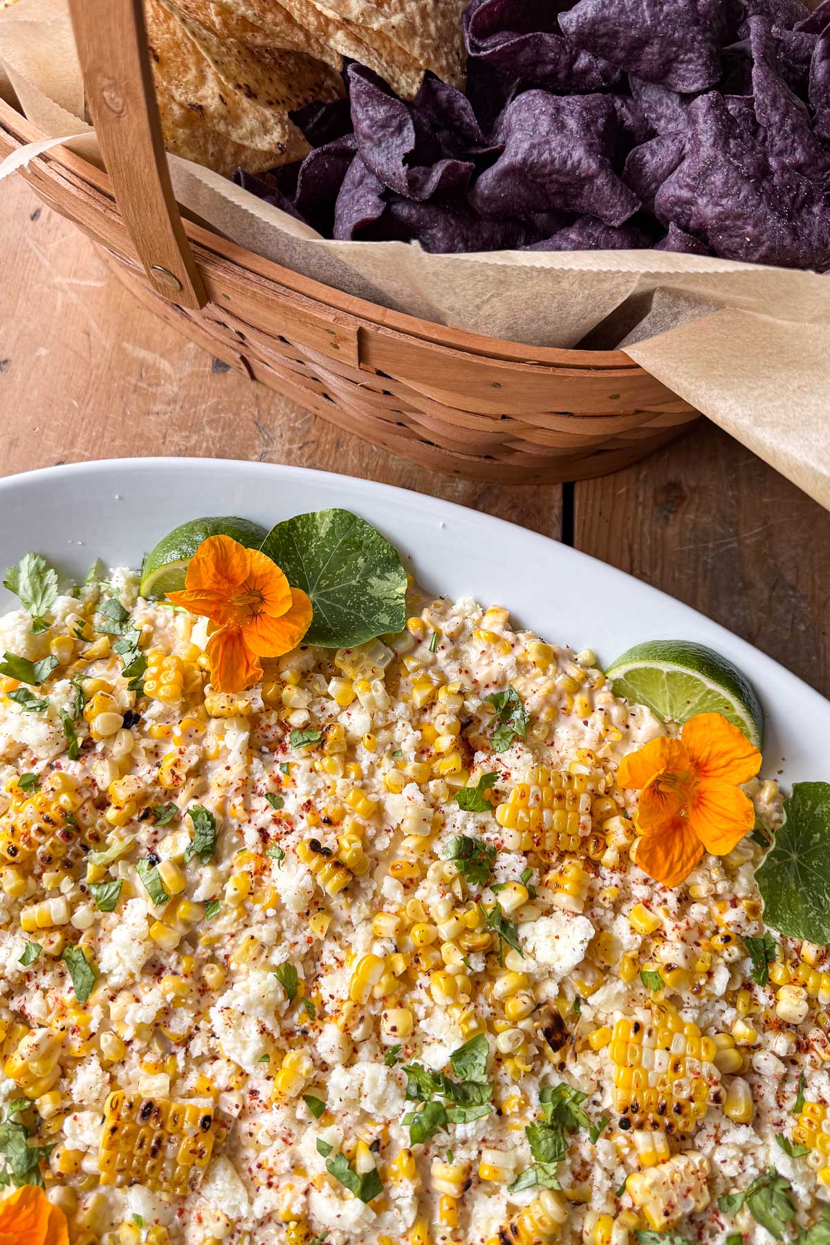 Elotรฉ corn dip with grilled corn, Cotija cheese, cilantro, lime, chile, and edible nasturtium flowers - served with assorted tortilla chips