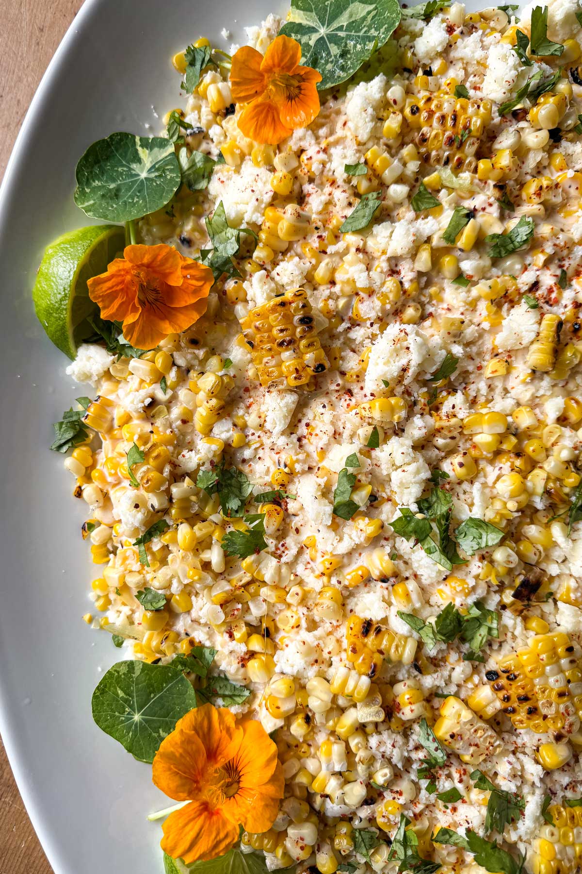 Elotรฉ corn dip with grilled corn, Cotija cheese, cilantro, lime, chile, and edible nasturtium flowers